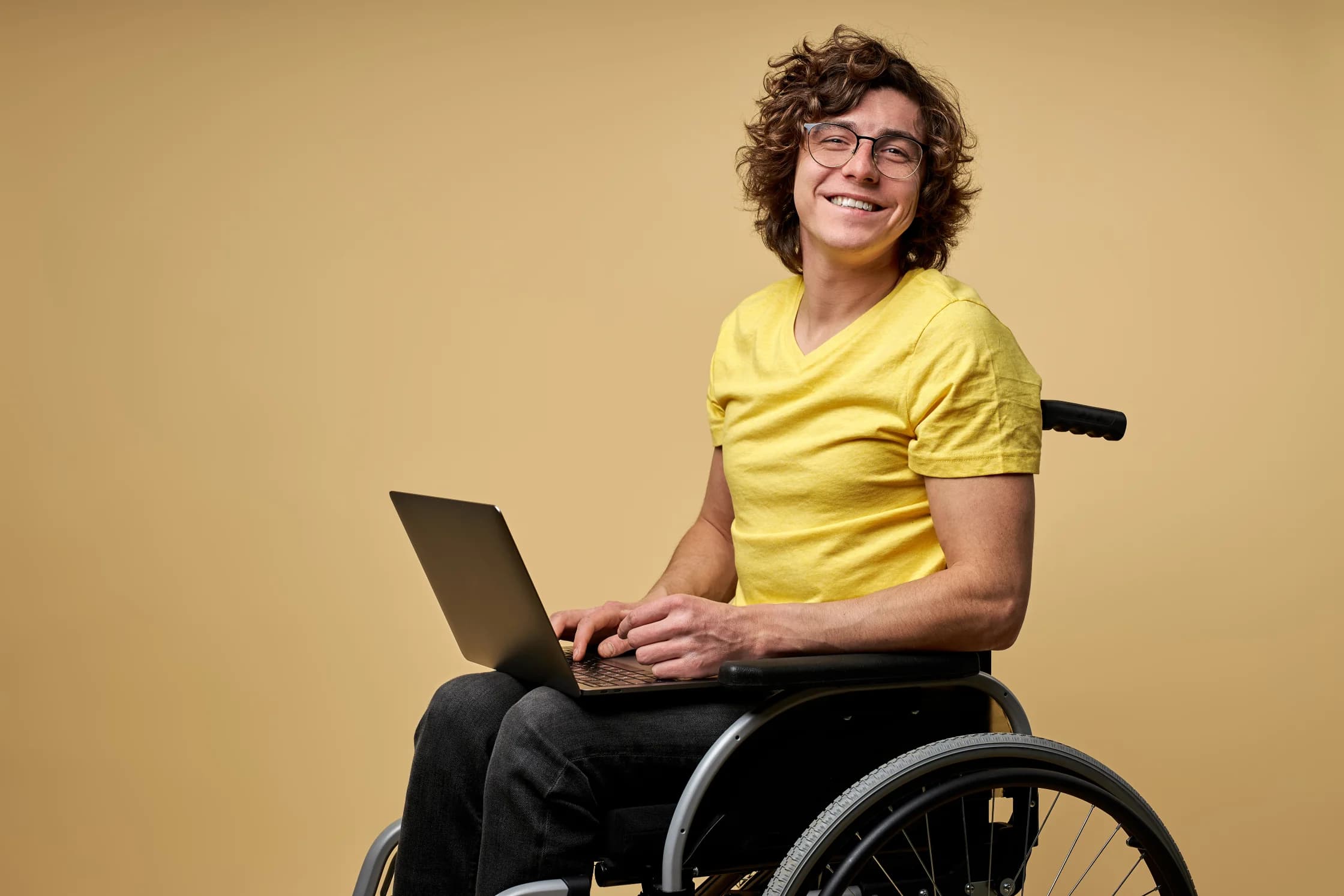 disabled man sits in a wheelchair with laptop