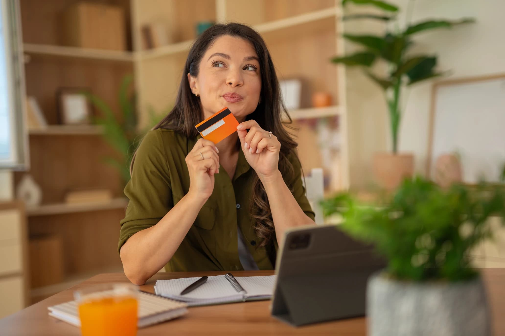 Woman holding a credit card and thinking