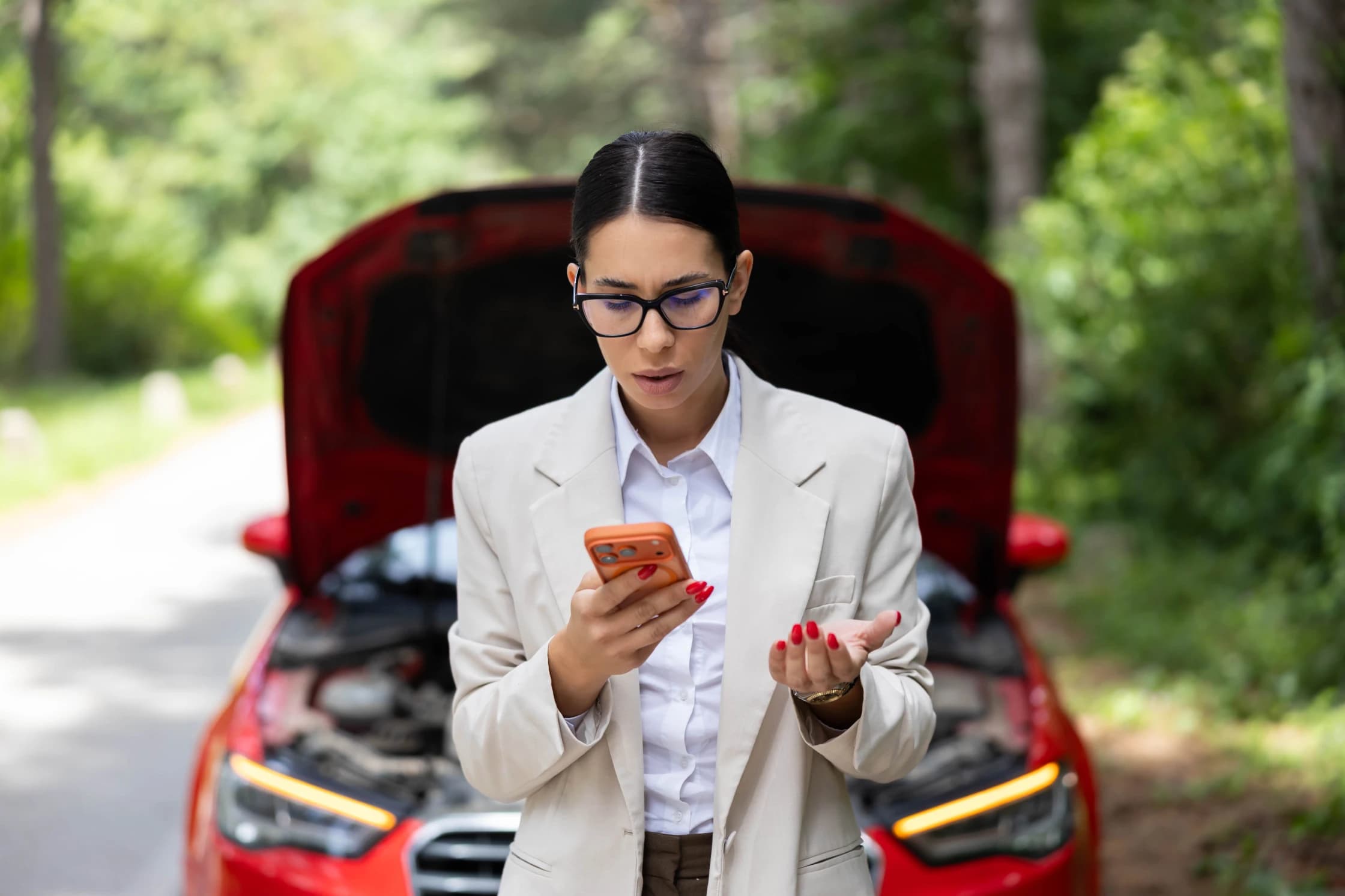 Frustrated woman standing next to her broken car