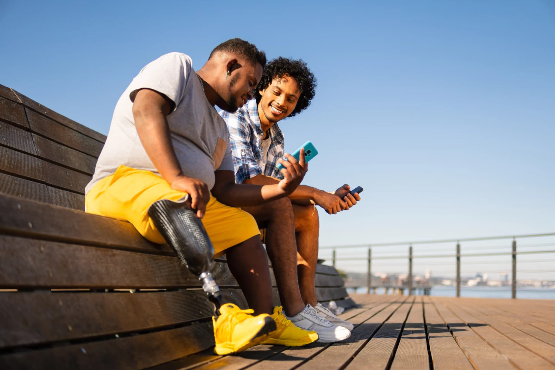 Disabled man showing mobile screen to friend Disabled man showing mobile screen to friend