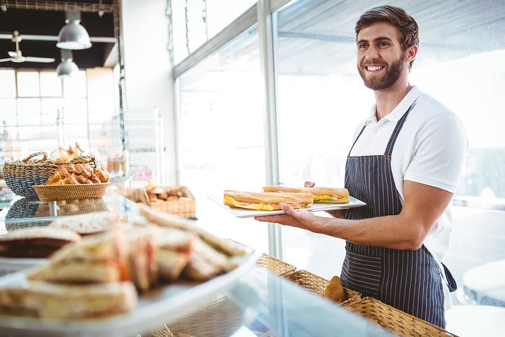 happy-worker-holding-sandwiches-at-the-backery-PMMU46L